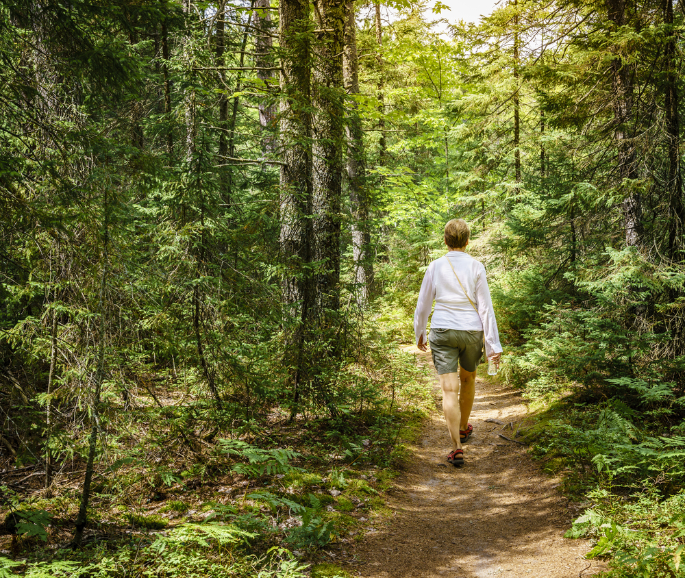 A woman wearing white t-shirt walking in the woods hiking in nebraska