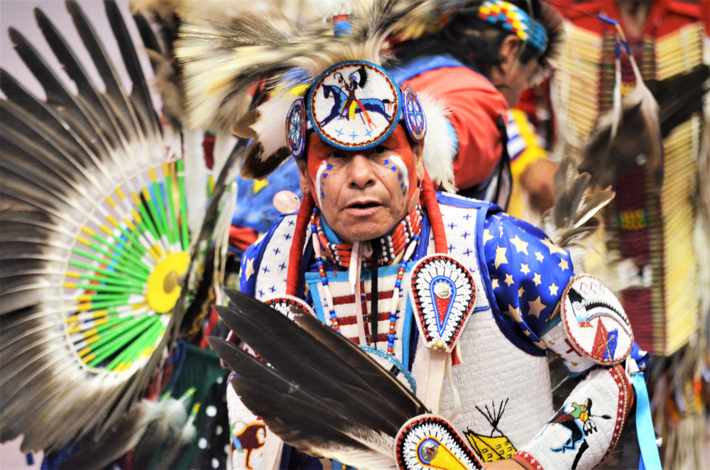 A man in colorful and feathered Native American regalia.