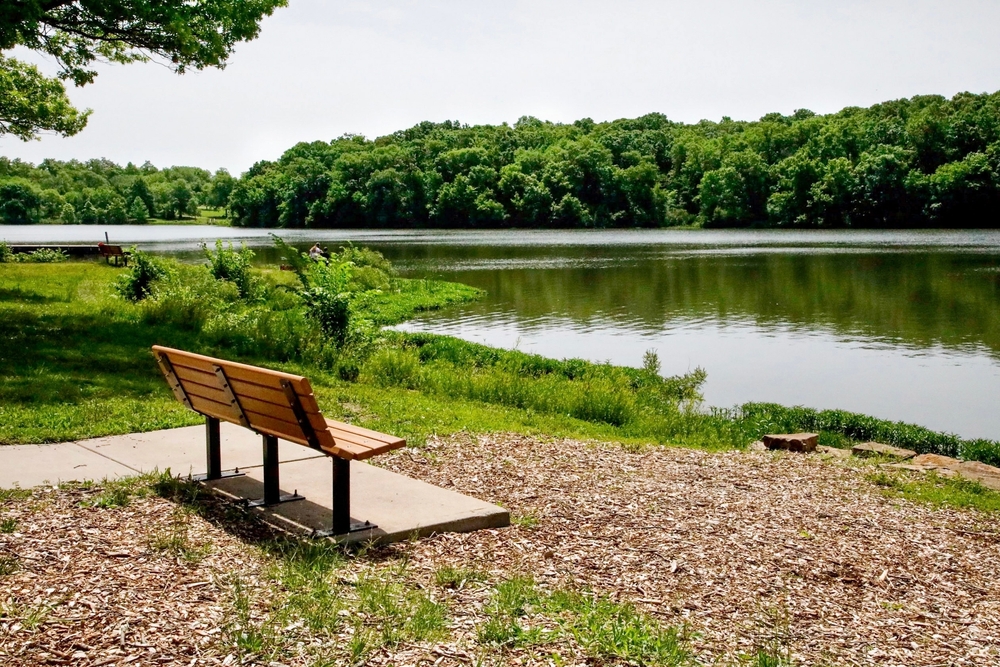 A bench sits near the lake in Shawnee Mission Park.