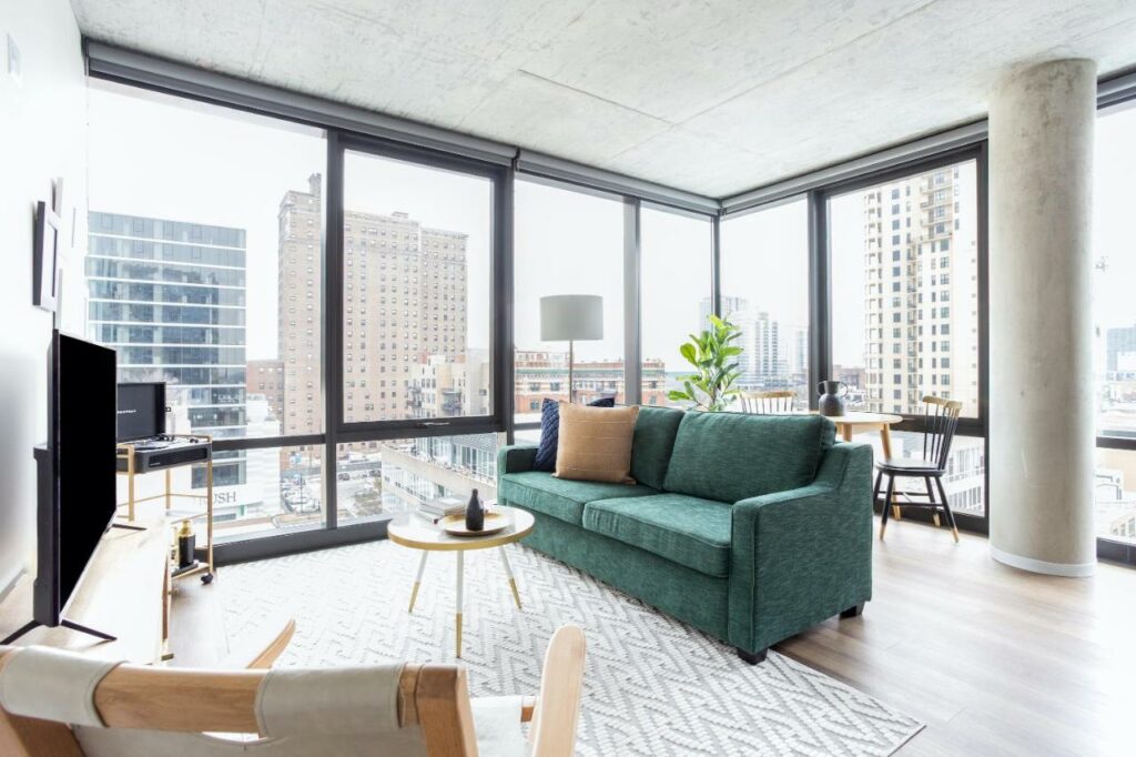 Living room space in a room at Sonder South Wabash with big windows looking out at the skyline.