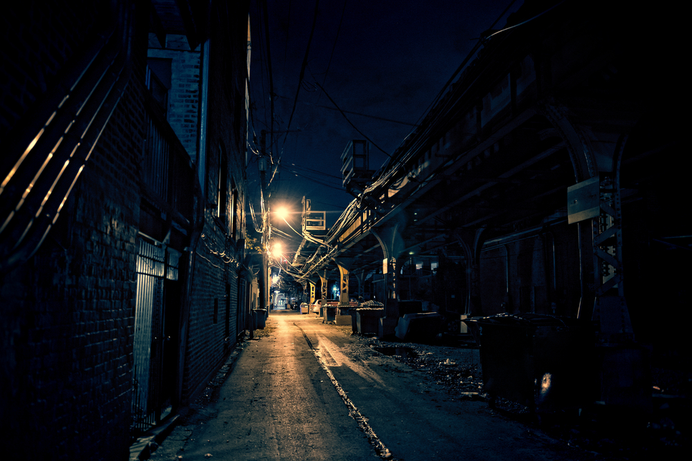 A dark alley with some street lights near a bridge in Chicago that looks eerie
