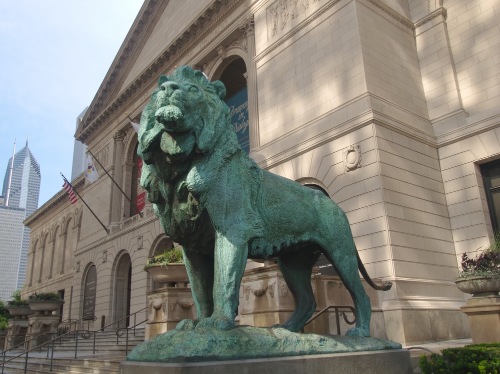 A bronze lion sculpture that has turned green in front of the Chicago Art Institute