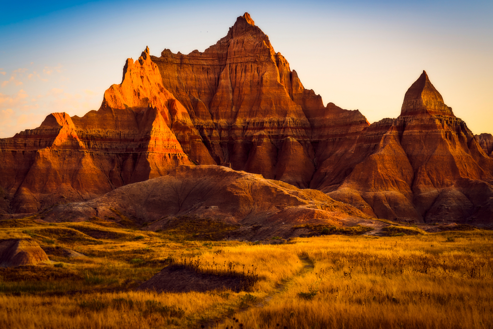 A view of one of the most iconic rock formations in Badlands National Park. It is a large and jagged dark orange rock formation