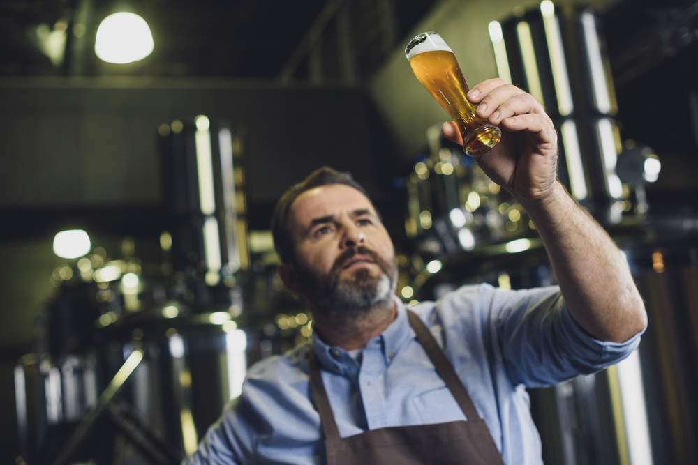 Man in a brewery holding a glass of ale to the light in an article about breweries in Cleveland