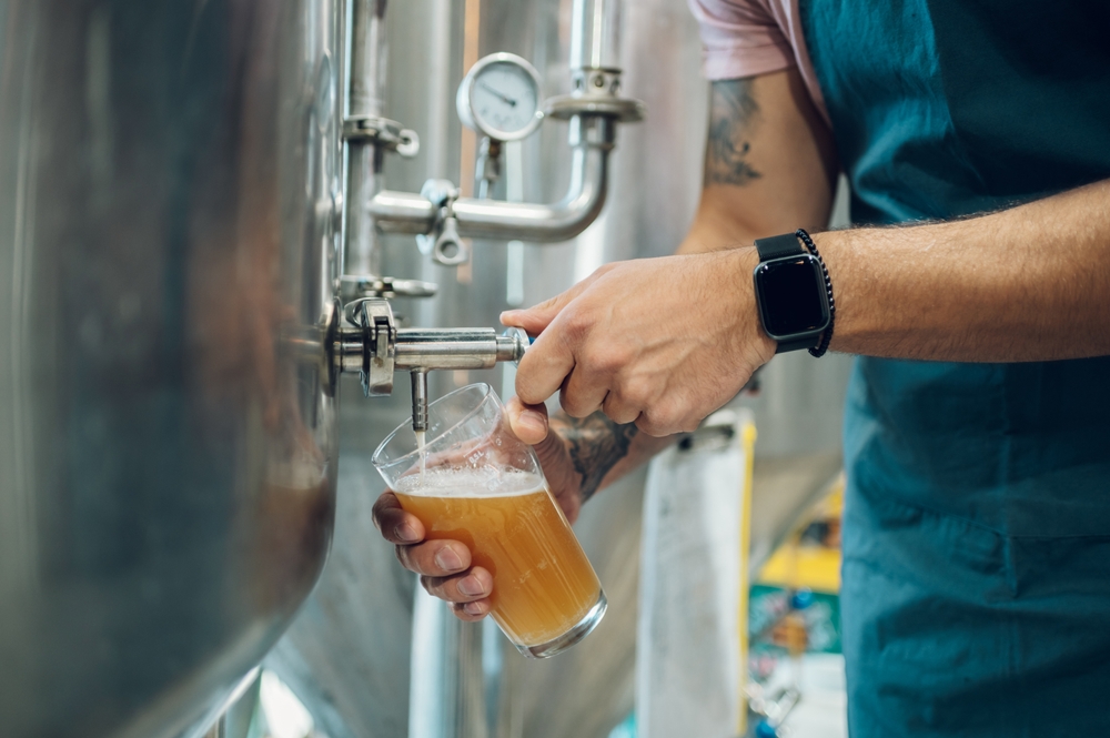 Man pouring beer out of a large metal keg in an artcile about breweries in Cleveland