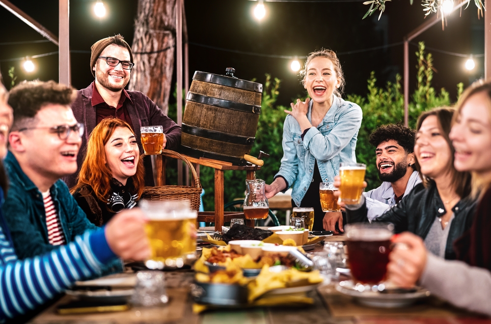 A large group of people on a patio at night enjoying beer, snacks, and laughing. Similar to what you'll find at breweries in Chicago. 