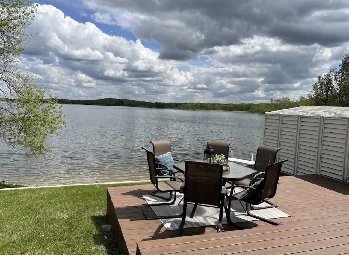 Patio table with chairs on deck with lake in background. Cabin in North Dakota
