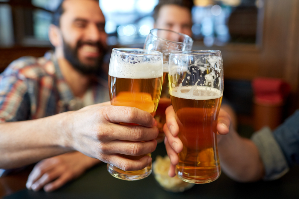 A close up image of three hands holding glasses of beer and clinking them together, similar to beer in breweries in Chicago.