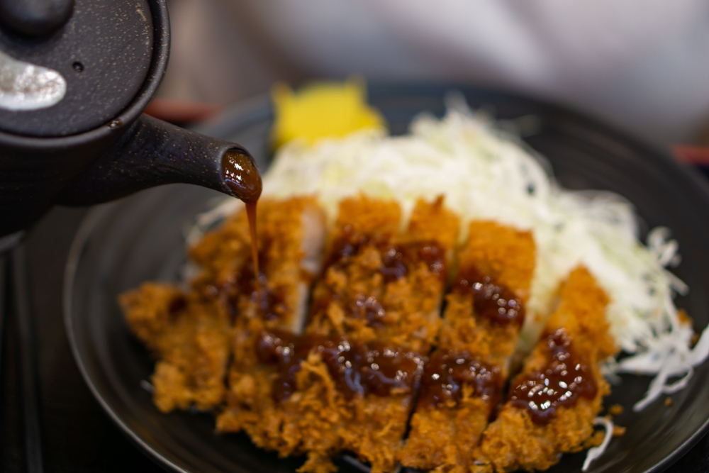 Japanese food called tonkatsu topped with delicious gravy or special tonkatsu sauce. It is served with rice and sause is been poured onto it. 