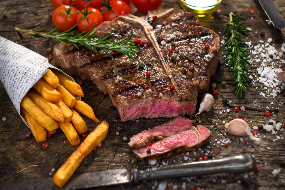 Steak on a wooden board with chips at the side in one of the restaurants in Akron