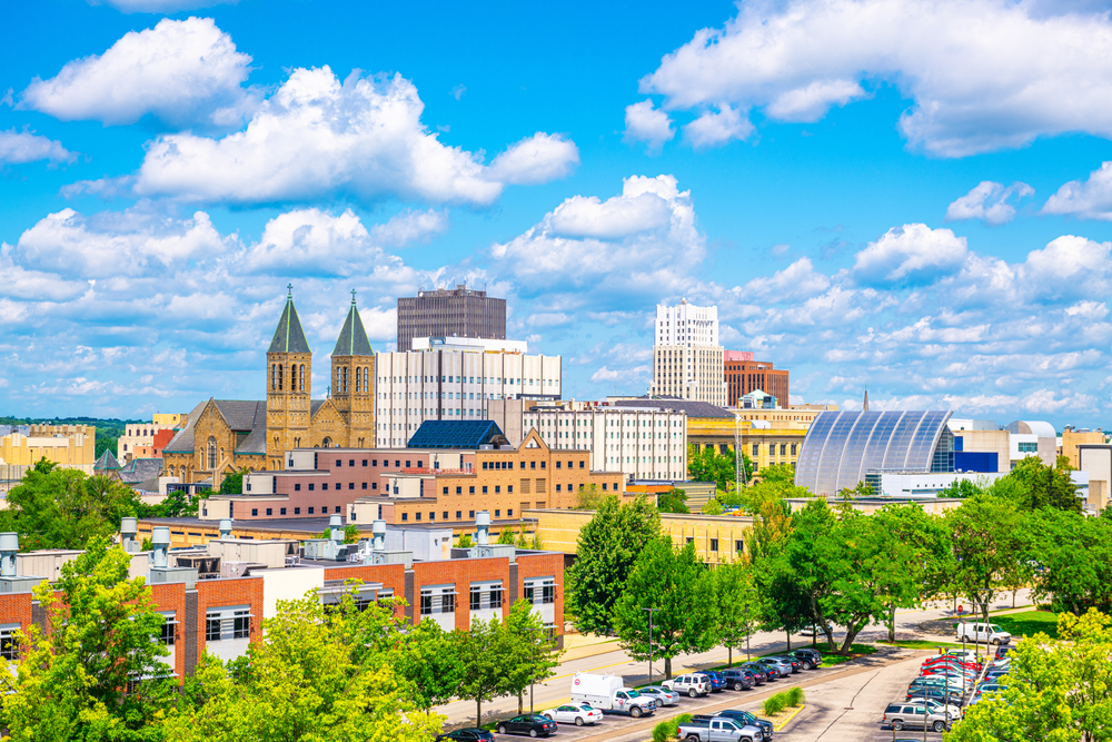 Downtown city skyline showing buildings in the background and trees and cars in the foreground. The article is about restaurants in Akron. 