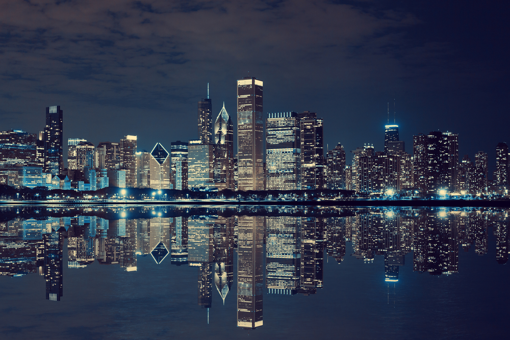The view of the Chicago skyline from the lake at night with the skyline all lit up.