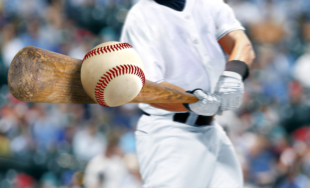 Baseball player hitting ball with bat in close up