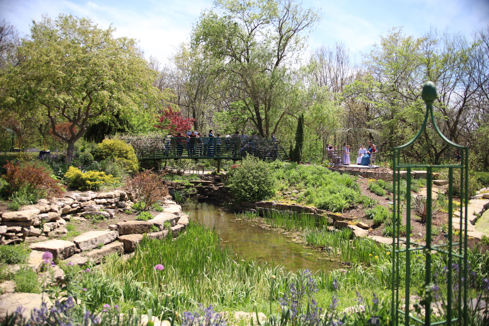 Beautiful pond and bridge Overland Park Arboretum.People are on the bridge  and in the garden. 