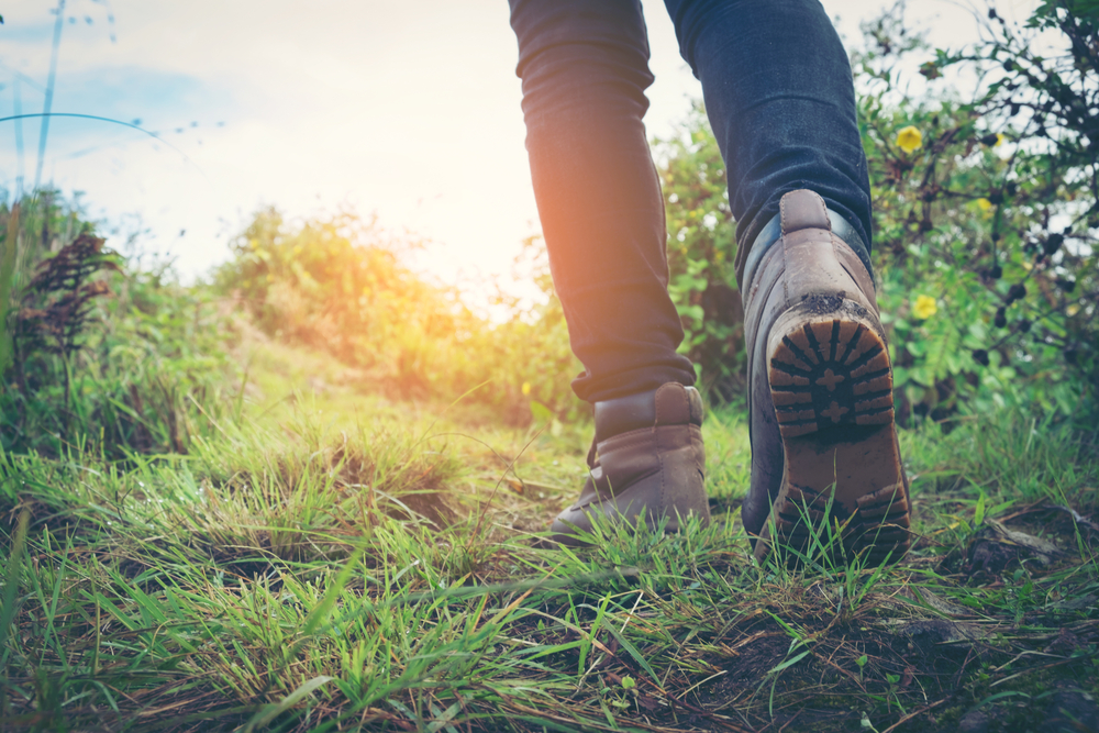 Hiking Boots walking through the grass taken from behind. Hiking is one of the things to do in Overland Park 