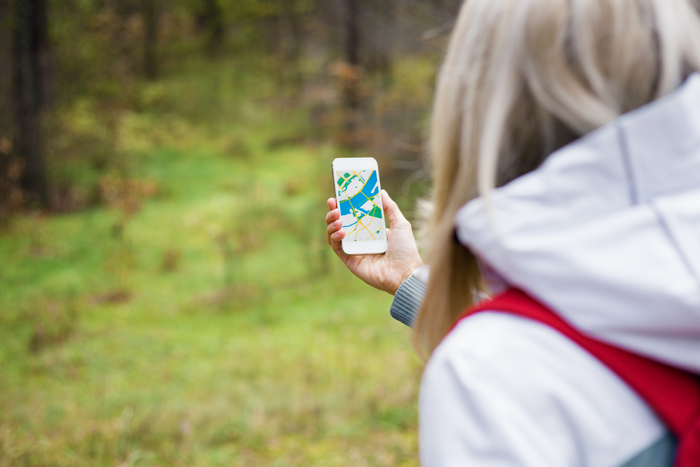 Women geocaching looking at her phone in the forest. 
