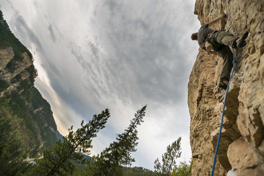 Picture of a climber taken from below showing rocks and trees 