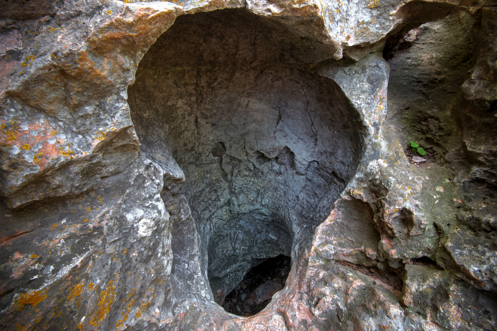 The small natural entrance hole of the Wind Cave surrounded by rock formations