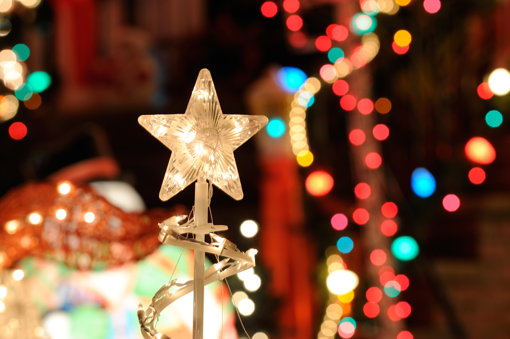 Close up of a star on a tree with lights in the background.