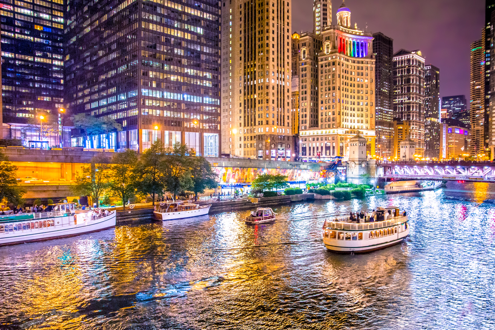 Night shot of a boat on the Chicago River with bright city lights.