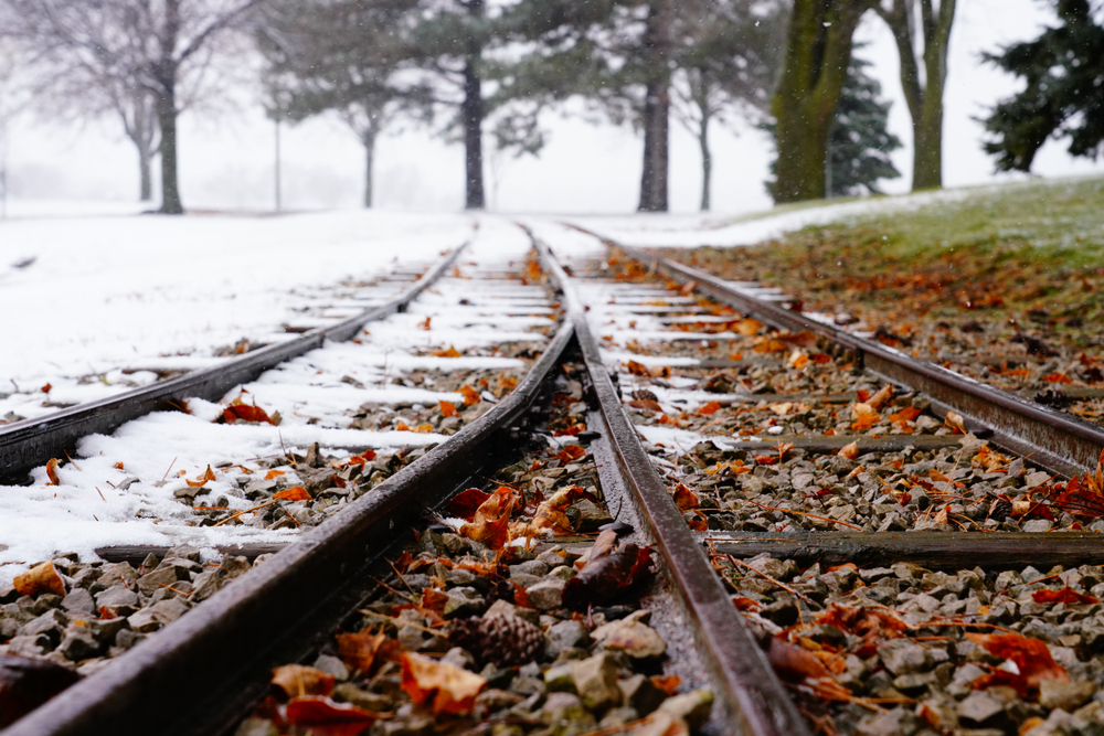 Railway tracks covered with snow and fall leaves
