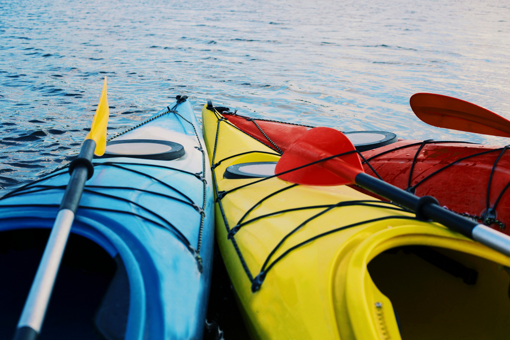 Three colorful kayaks on the lake shore.