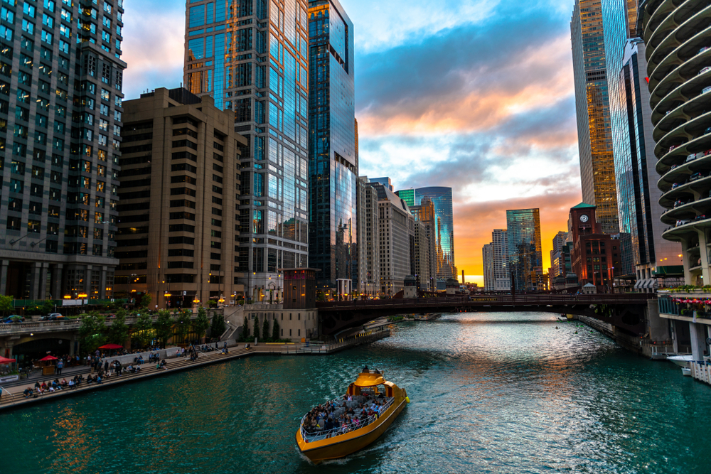 A yellow speedboat heading down the Chicago River at sunset.