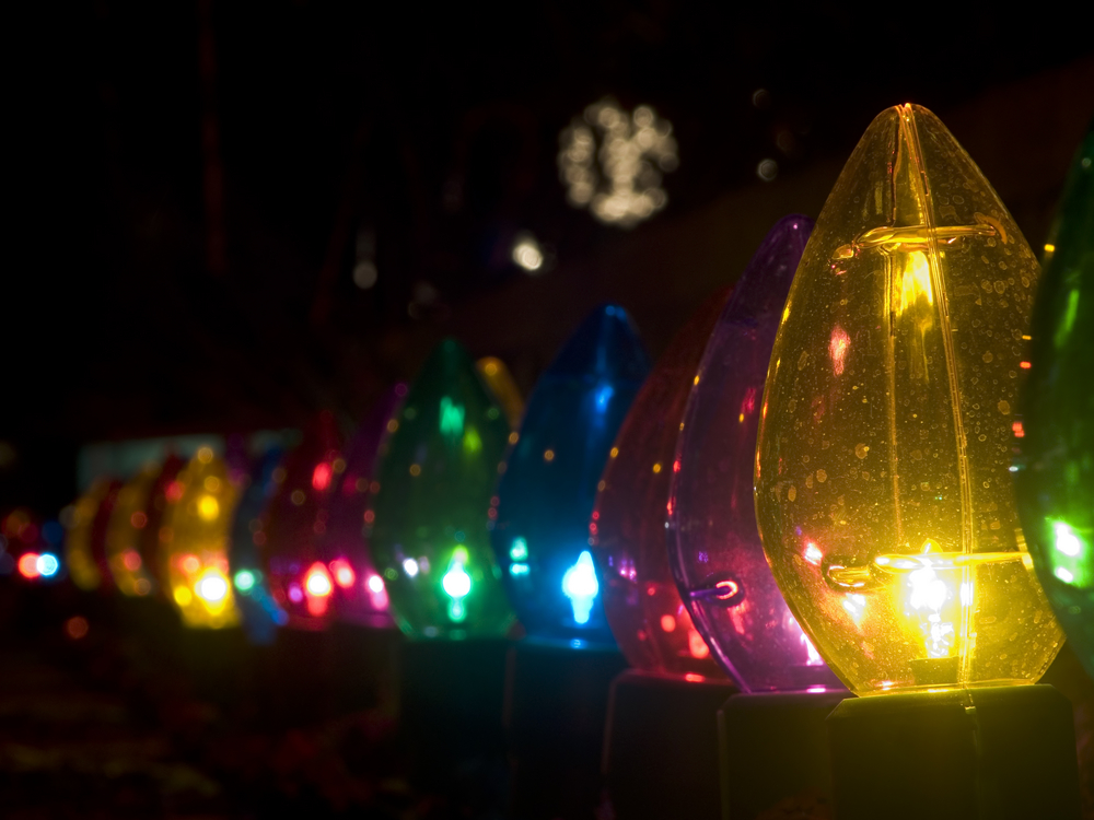 Row of outdoor oversized Christmas lights - dark - night image - blurred white lights in background