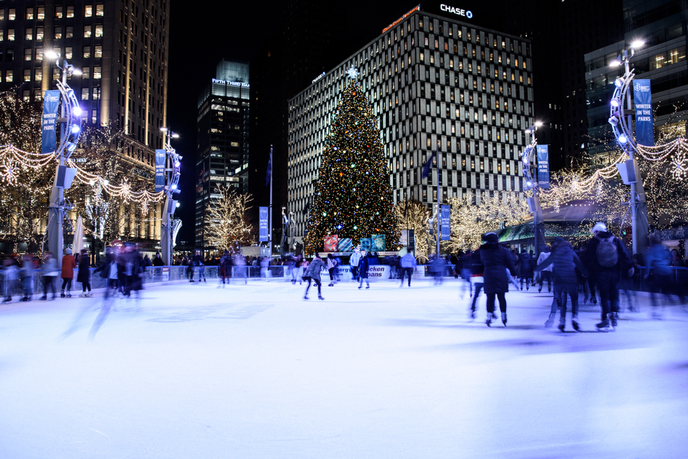 People Ice Skating in Campus Martius in Downtown Detroit Michigan. The Christmas Tree sparkles in the background 