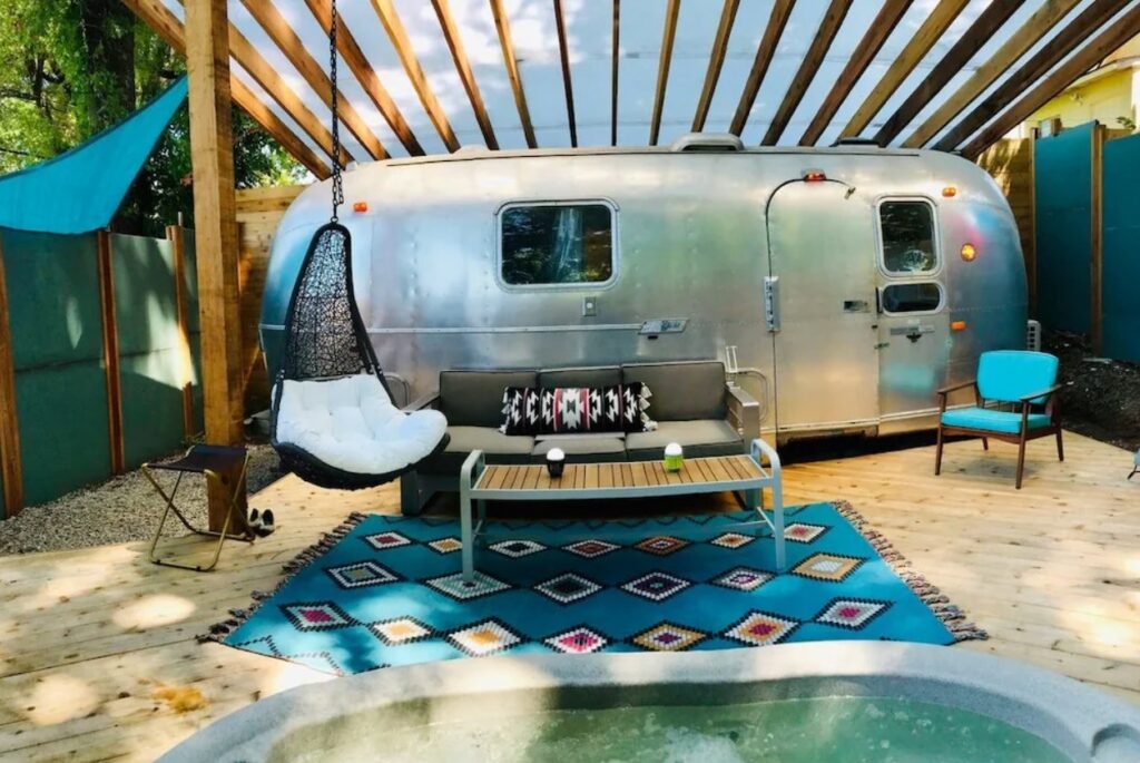 A silver airstream camper with a sitting area in front of it, one of the best Airbnbs in Kansas City Missouri