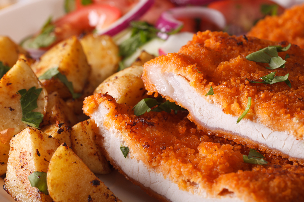 Chopped schnitzel macro and fried potatoes on a plate. horizontal. The article is about restaurants in Chicago. 