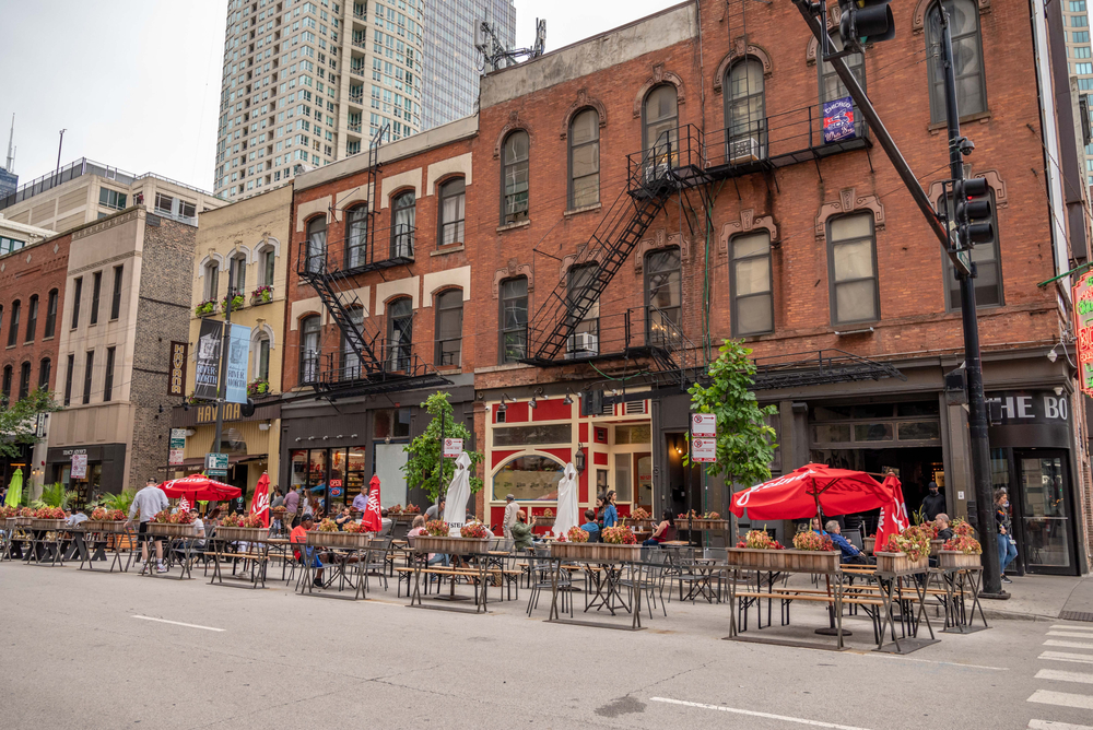 People eating on the street in Chicago with building in the background. The article is about restaurants in Chicago. 