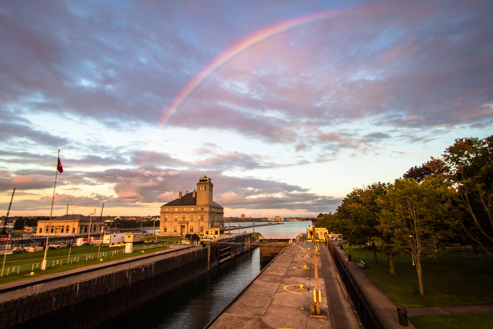 Looking at the Soo Locks, one of the best things to do in Sault Ste Marie, with a rainbow across the sky