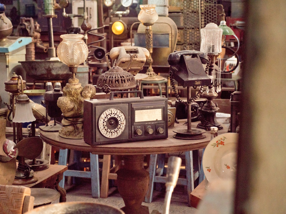 Antique street shop with old, vintage items. There is an old radio and phone in the front  