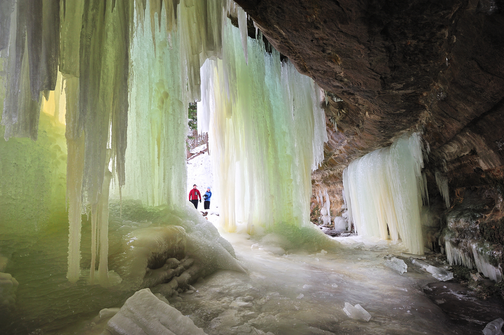 People entering ice caves formed by frozen waterfall winter in michigan