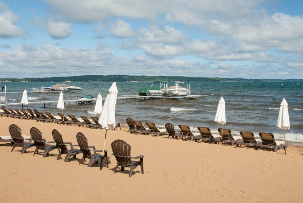 Chairs lining the beach, looking out at the lake with docked boats.