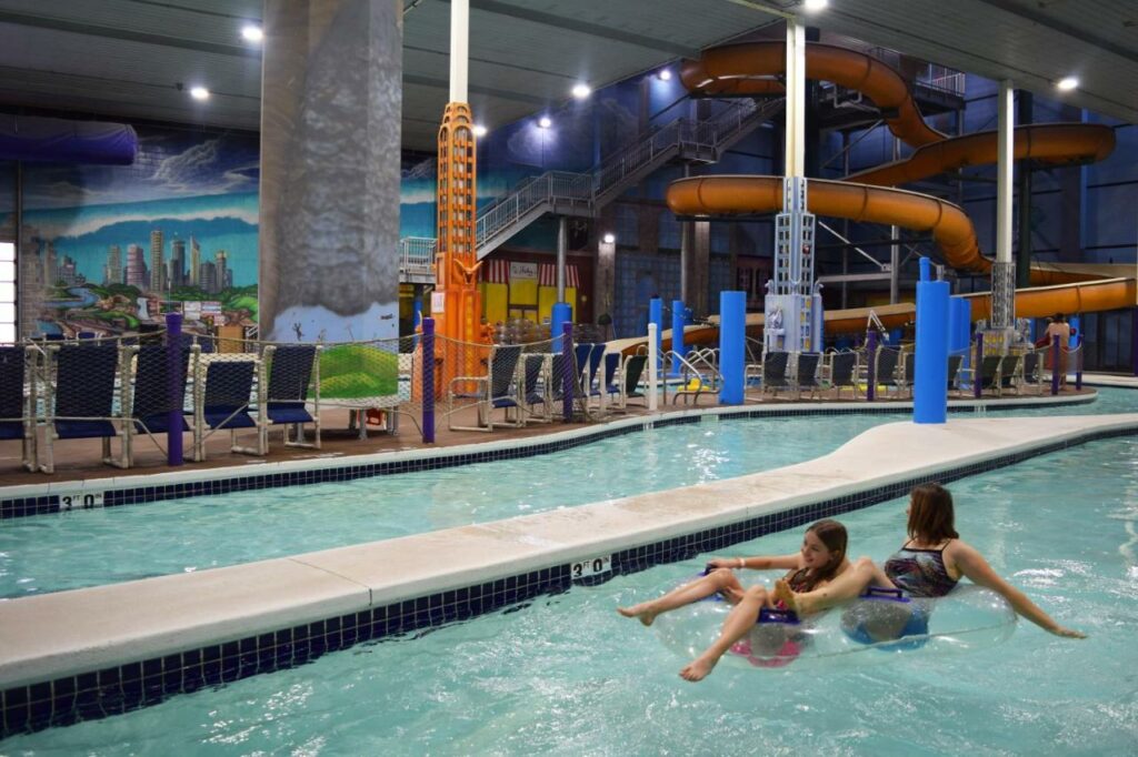 Two people in an innertube on an indoor lazy river at one of the best resorts in Wisconsin. Behind them is a large indoor waterslide. 