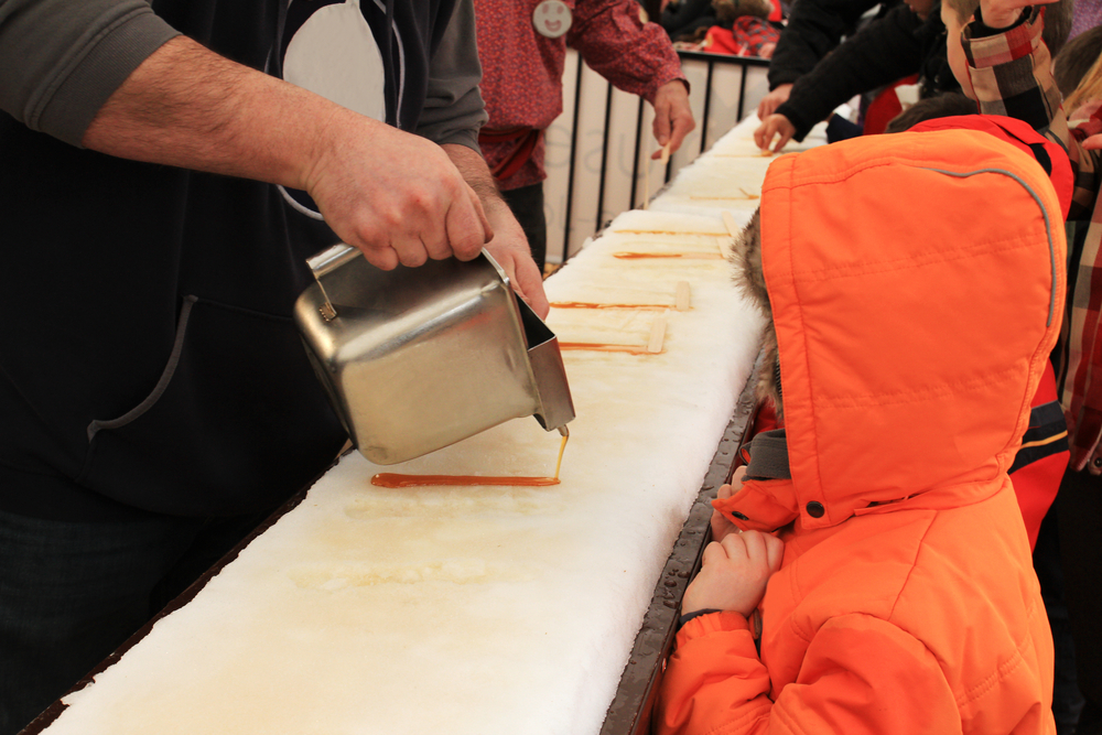 A small child waiting to try a maple syrup stick at a maple syrup festival during winter in Ohio