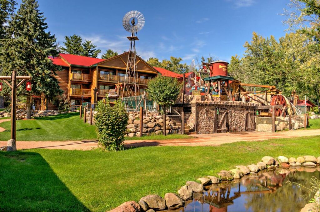 A log cabin style building with a small waterpark in front of it, one of the best resorts in Wisconsin