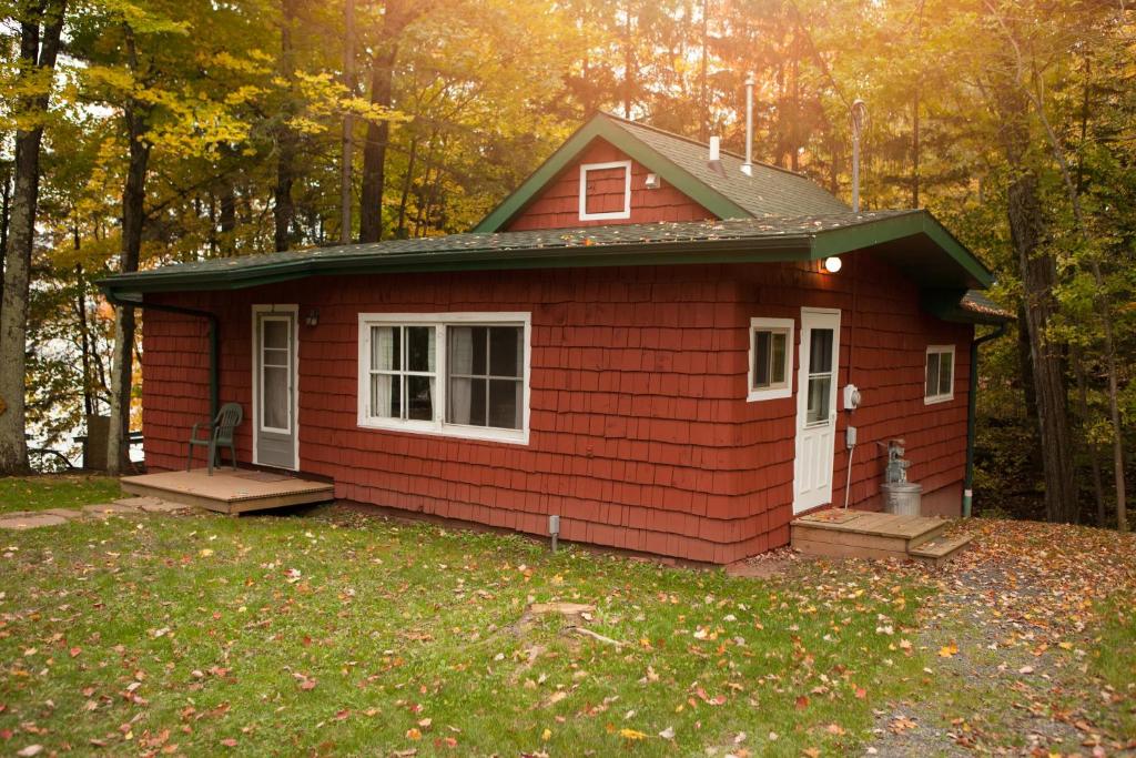 A cute red cabin surrounded by woods in the fall 