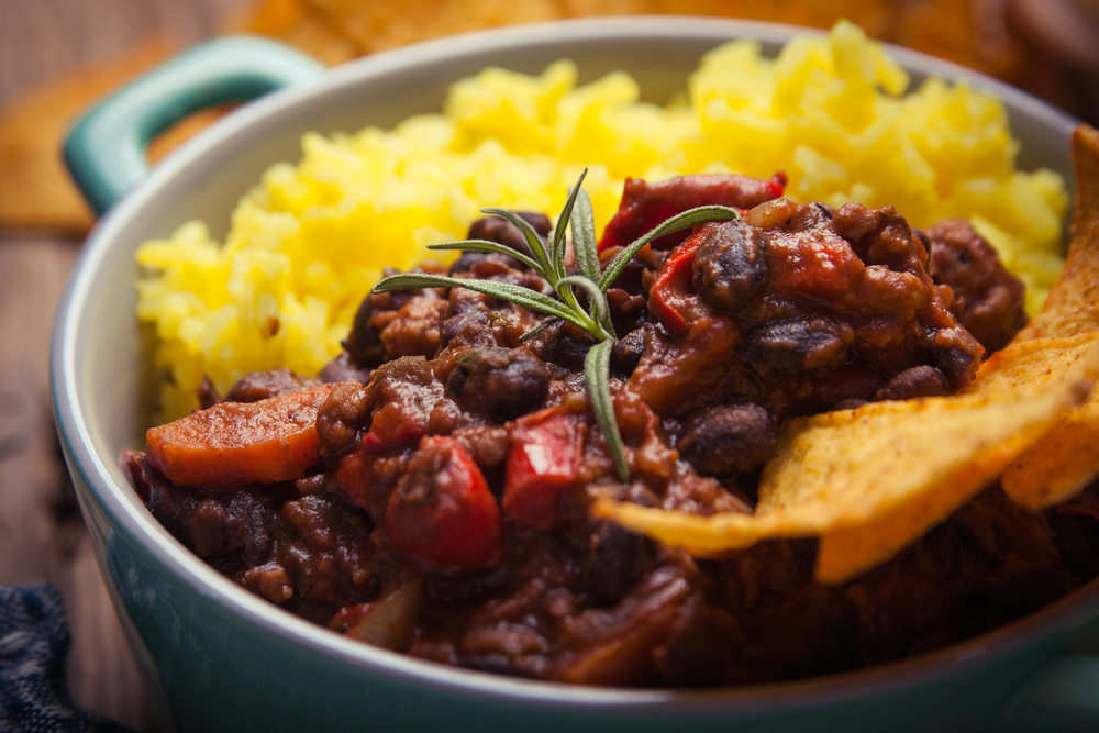 Chilli in bowl with rice and tortills chips on the side 