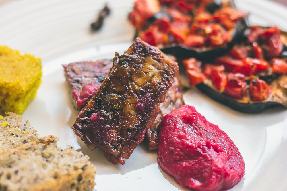 Fake steak on plate surrounded by vegetables. 