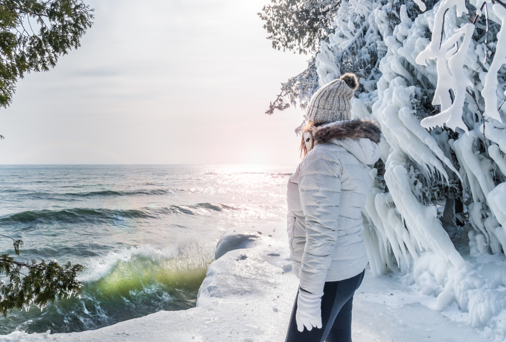 woman standing on icy shoreline at Cave Point Park in winter in Door County 