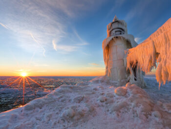 Sunrise beside a lighthouse covered with ice winter in michigan
