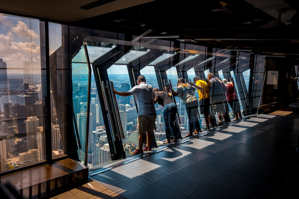 A group of people looking down at the Chicago skyline from the 94th floor of a building