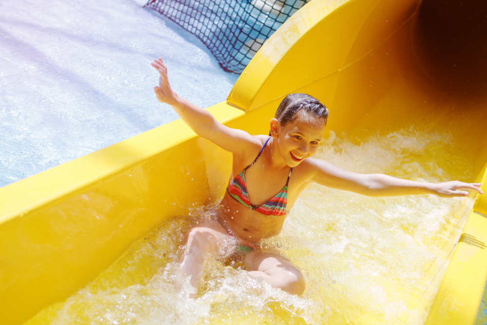 Young girl enjoying a yellow colored water slide things to do in billings