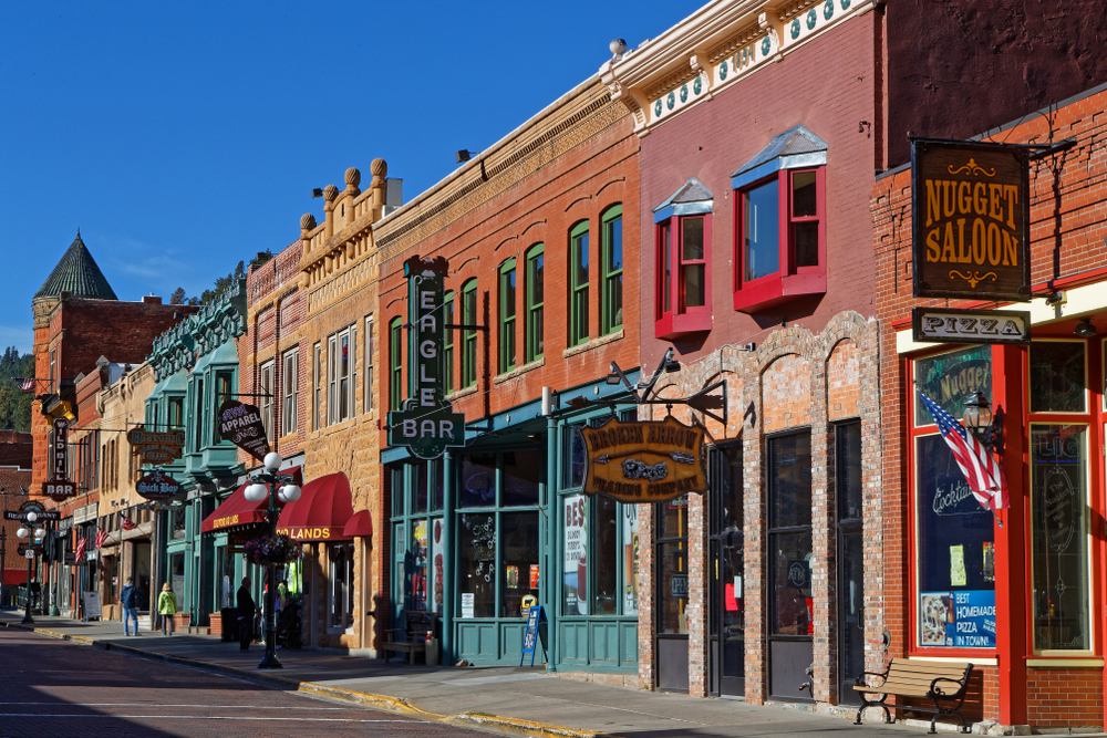 Sunny Main Street in Deadwood featuring 1800s architecture and bars.