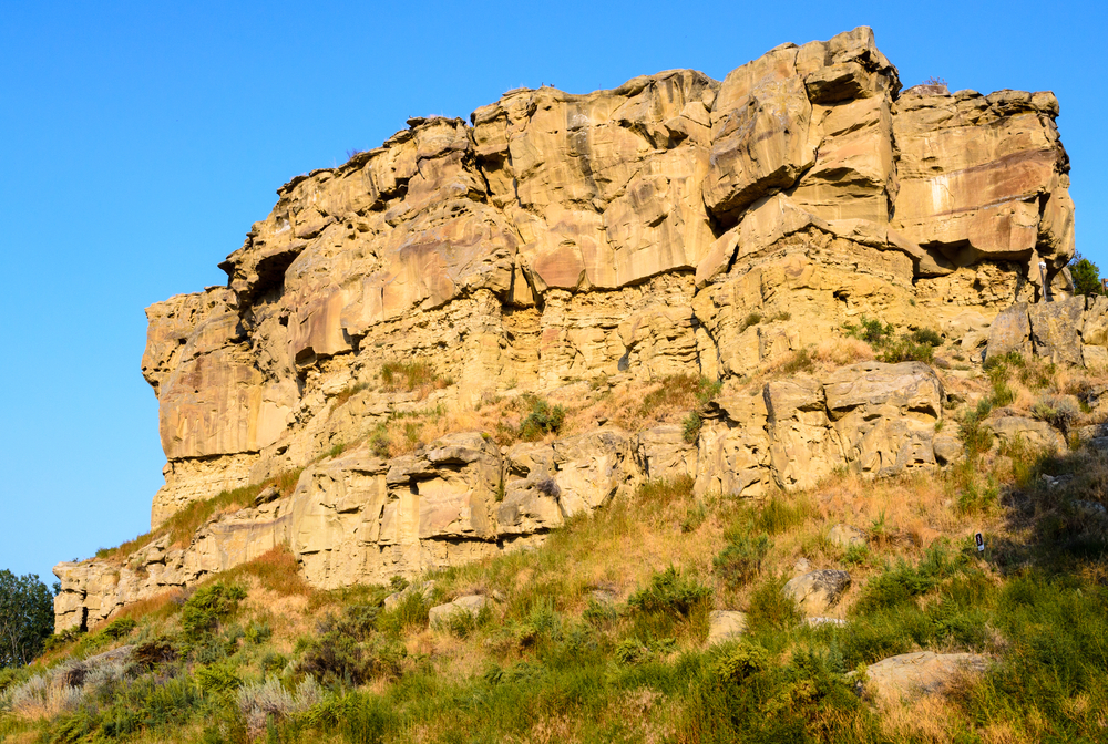 The rugged Pompeys Pillar standing tall against a blue sky at one of the best national parks in Montana.