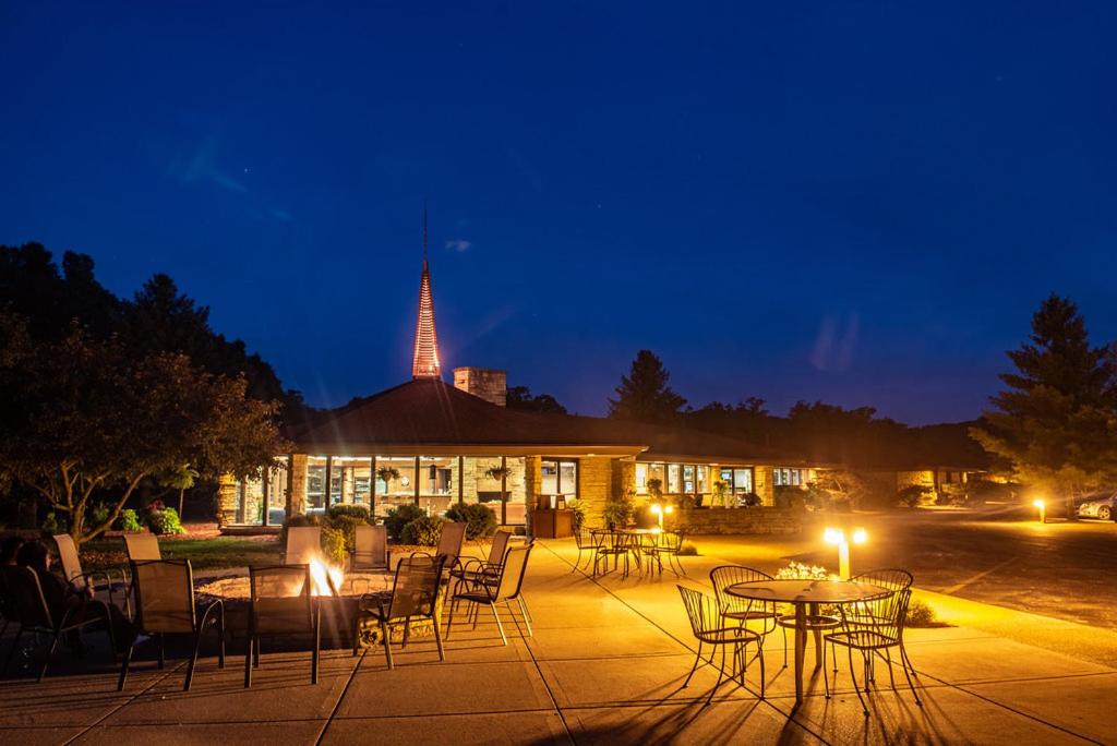 Exterior nighttime photo of the Spring Valley Inn with a burning fire surrounded by chairs.