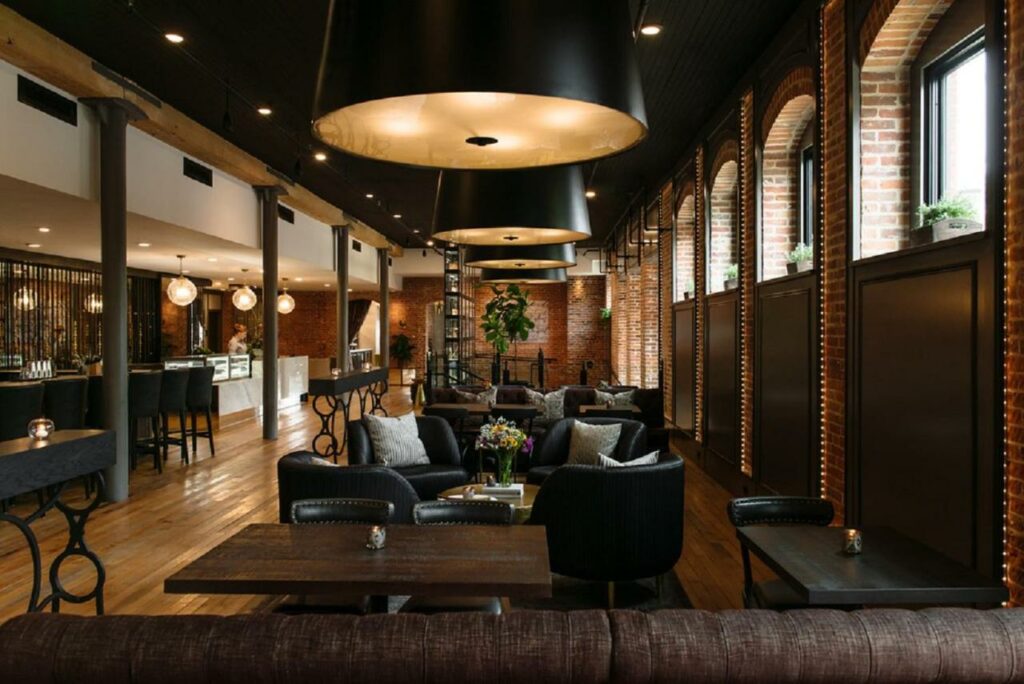 Modern lounge area at the The Charmant Hotel with brick walls and black furnishings.
